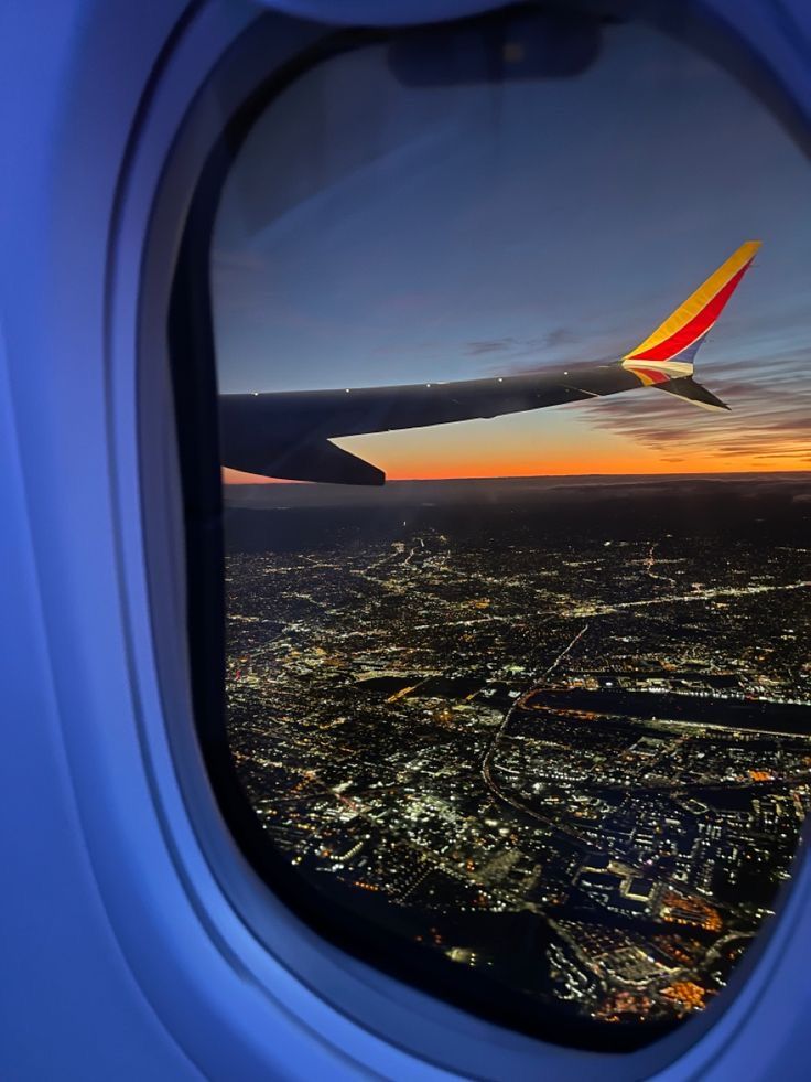 the view from an airplane window at night, looking down on city lights and buildings