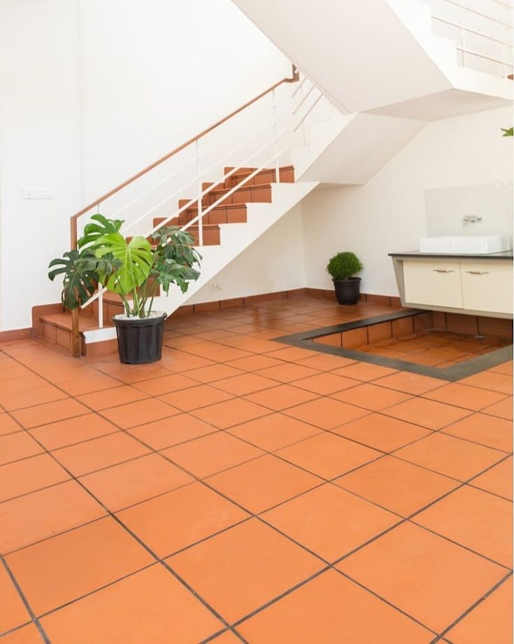 there is a potted plant on the floor in front of a stair case and table