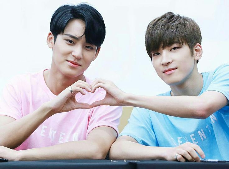 two young men sitting next to each other with their hands in the shape of a heart