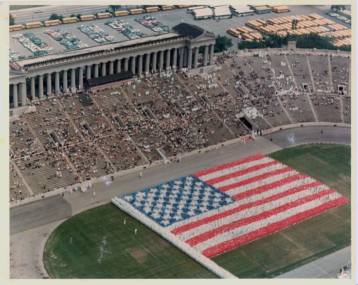 an aerial view of a large american flag in the middle of a stadium with people watching