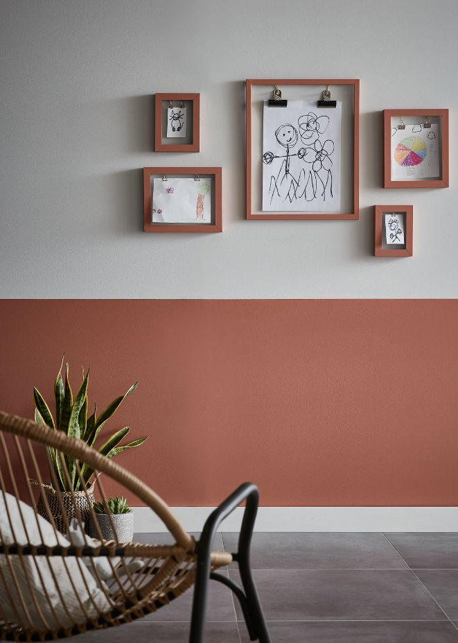 a chair and some pictures on the wall in a room with tile flooring that looks like it has been painted red