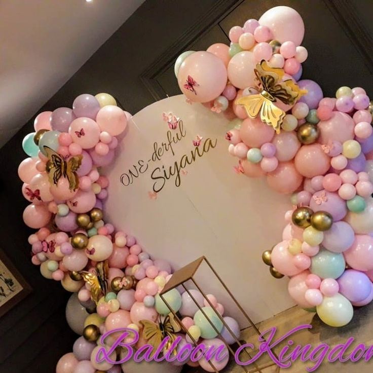 a balloon arch is decorated with pink, blue and gold balloons in the shape of a heart