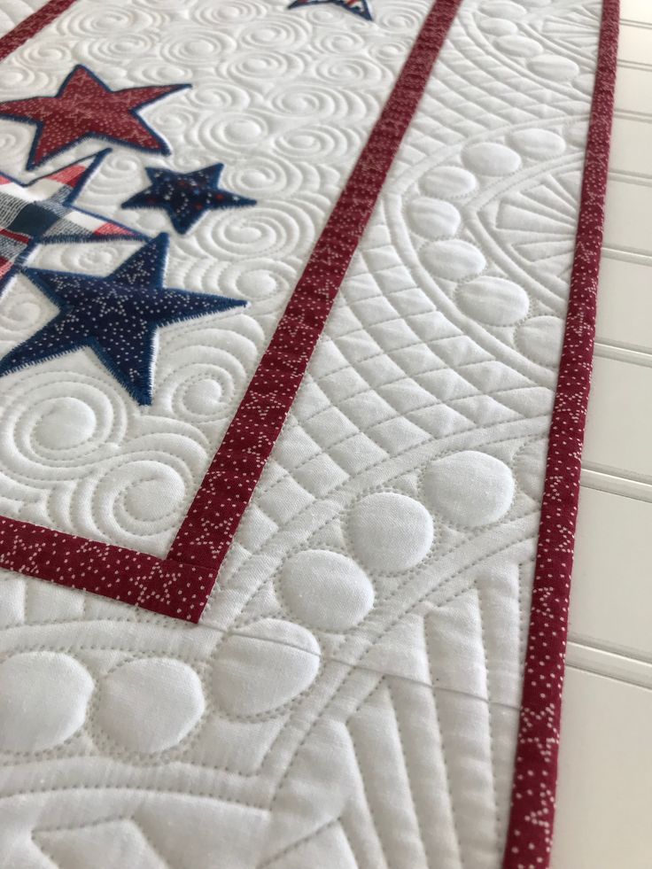 a quilted table runner with red, white and blue stars in the center on top of it