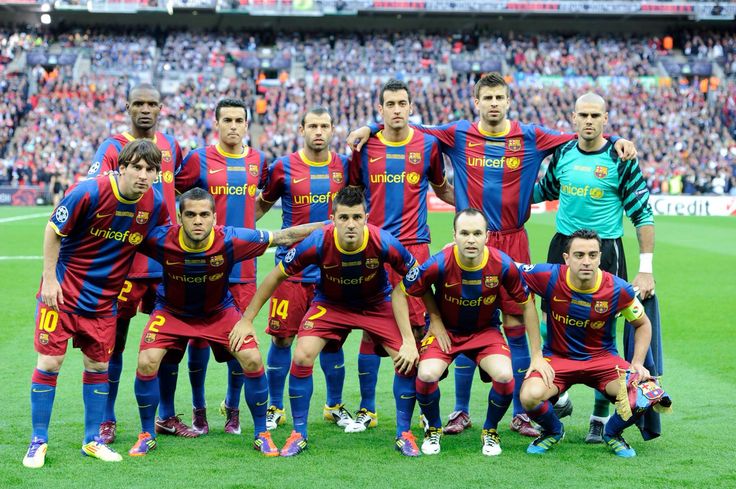 a group of soccer players pose for a team photo on the field in front of an audience