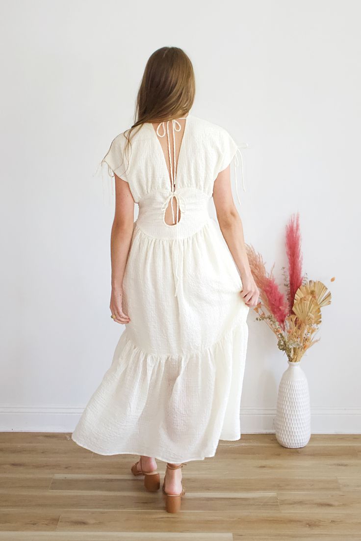 Get ready to turn heads in the stunning Krishna Maxi Dress! Its flowy silhouette and delicate detailing make it the perfect choice for any occasion. With its versatile design, you can easily dress it up or down for a look that exudes confidence and style. Embrace your inner goddess and add this dress to your wardrobe today! Airy Flowy V-neck Dress, Cream Maxi Dress With Flowy Skirt, Feminine Flowy Boho Dress For Garden Party, Flowy Airy Dress For Brunch, Cream Maxi Length Dress With Flowy Skirt, Flowy Midi Dress With Tie Back, Flowy Brunch Midi Dress With Tie Back, Feminine Tie Back Maxi Dress For Day Out, Cream Flowy Dress With Smocked Back