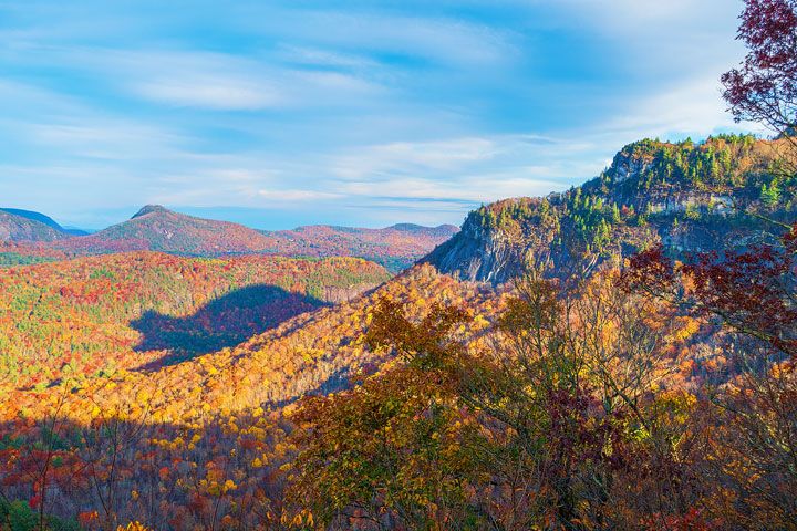 the mountains are covered in autumn foliage and trees with orange, yellow, and green leaves