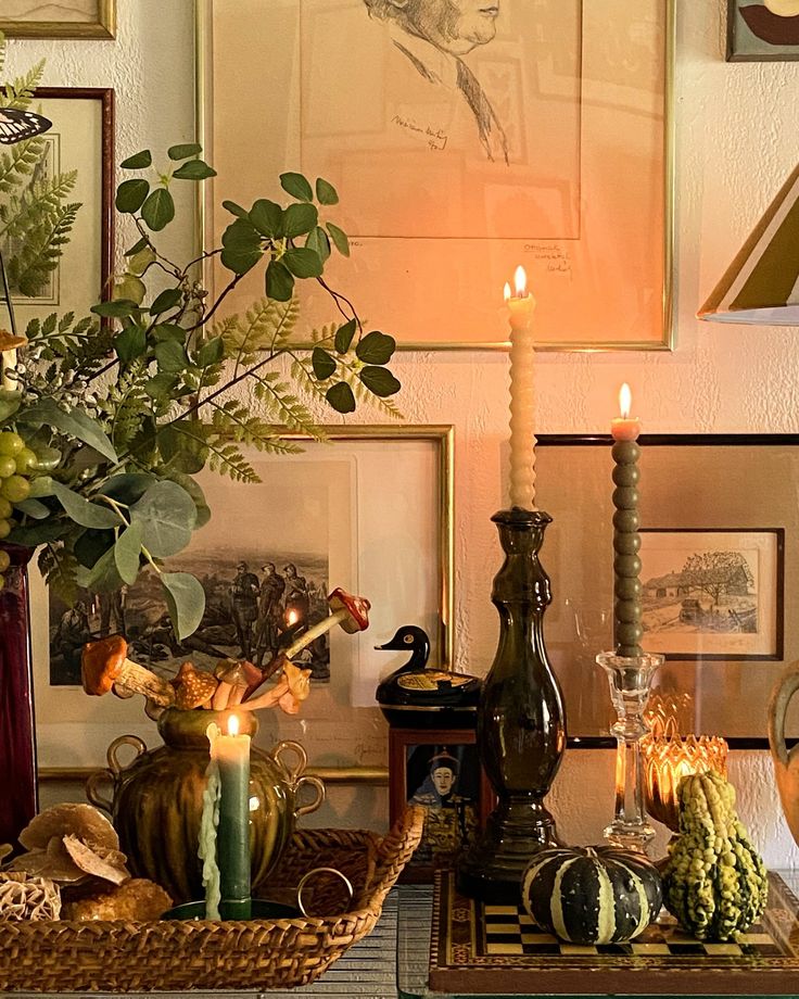 a table topped with vases filled with flowers and candles next to pictures on the wall