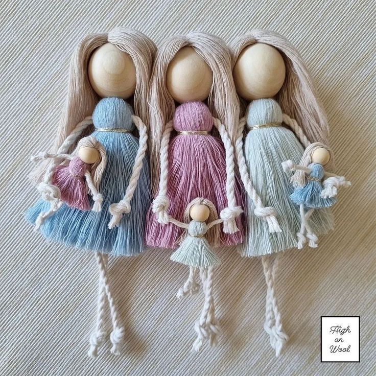 three wooden dolls with braids and tassels on top of a white surface