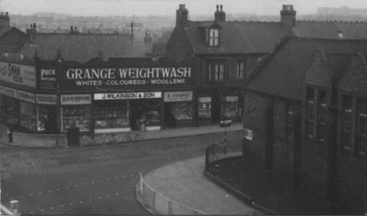 an old black and white photo of a street corner with buildings on both sides that have large signs reading orange weightwash