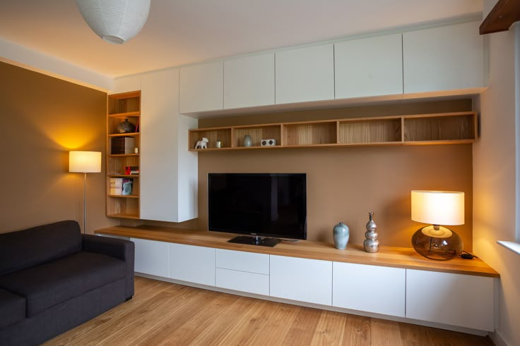 a living room filled with furniture and a flat screen tv on top of a wooden shelf