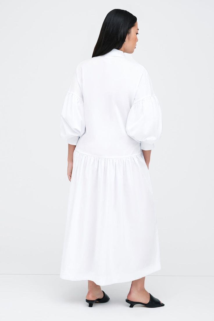 Meet our Ada Dress, the ultimate warm weather staple. She's a midi shirtdress handcrafted from 100% European poplin cotton, featuring pockets and a dropped gathered waistline that falls over your frame with ease. Her clean lines and sharp collar harmonize with dramatic dropped shoulders and full-bodied sleeves, elevating your style for any occasion.[SPLIT] Shannon, in white, is 5'8" (173 cm) tall, wearing size M. Yada, in light blue, is 5'9" (175 cm) tall, wearing size XS. Maritza, in black and Tunic Hoodie, Shirtdress, Tunic Dress, First Look, Cotton Dresses, Clean Lines, Warm Weather, Sundress, Red Dress