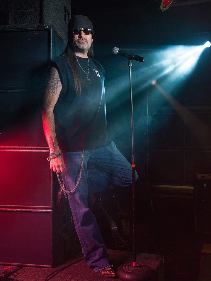 a man standing in front of a microphone on top of a stage with lights behind him