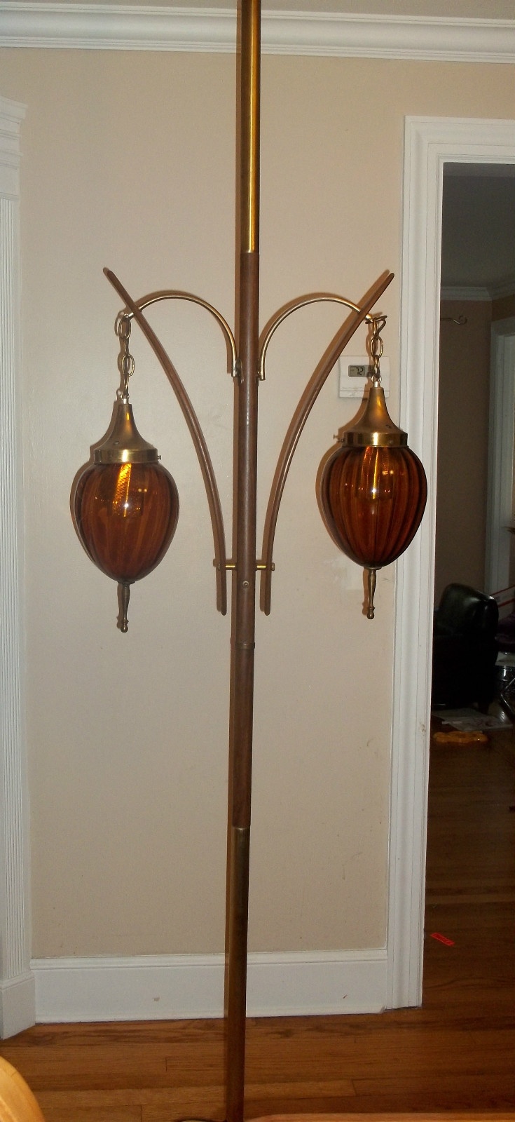 two lamps are hanging from a pole in a room with hardwood floors and white walls