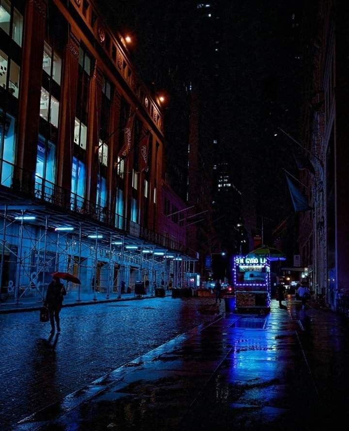 a person with an umbrella is walking down the street at night