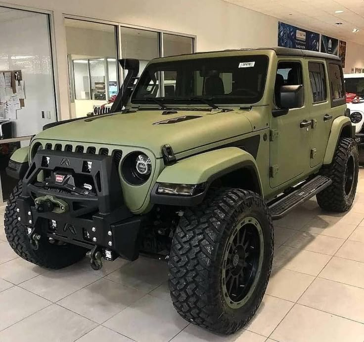 a green jeep is parked in a showroom