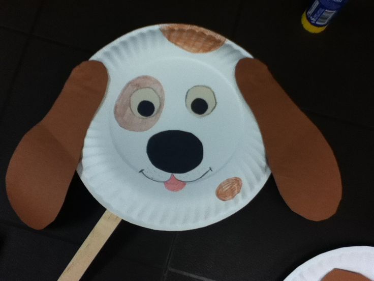 a paper plate with a dog face on it and a wooden stick sticking out of it