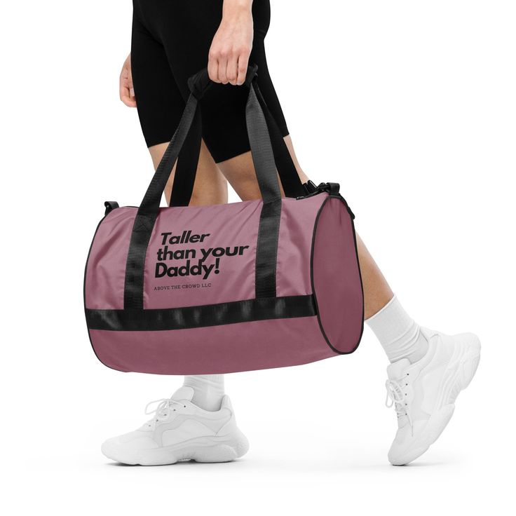 a woman carrying a pink duffel bag that says, taller than your daddy