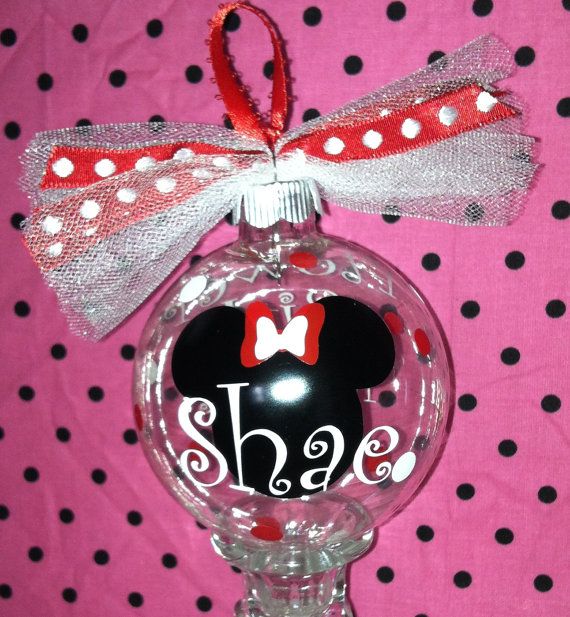 a minnie mouse ornament is hanging on a pink polka dot background with red and white ribbon