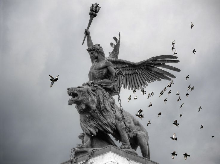 the statue has many birds flying around it and there is a bird in the sky