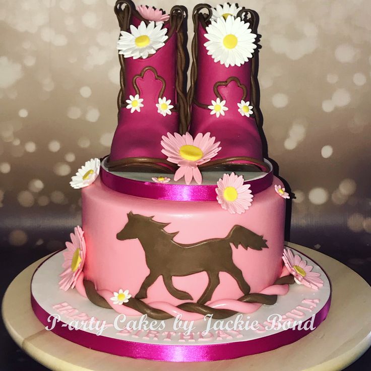 a pink cake decorated with boots and flowers