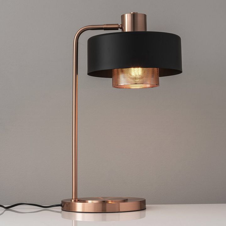 a table lamp with a black shade on it and a white wall in the background