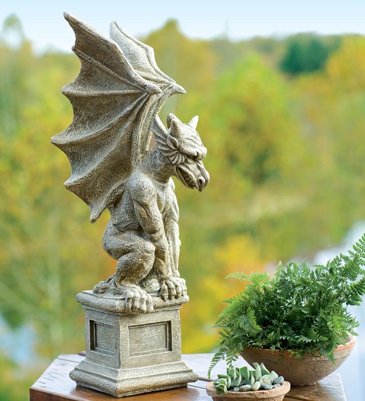 a statue of a dragon sitting on top of a table next to a potted plant