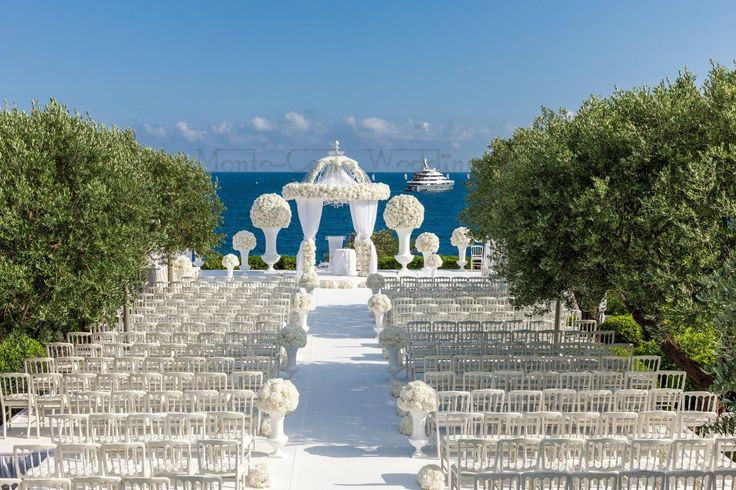 an outdoor wedding setup with white flowers and greenery on the aisle, overlooking the ocean