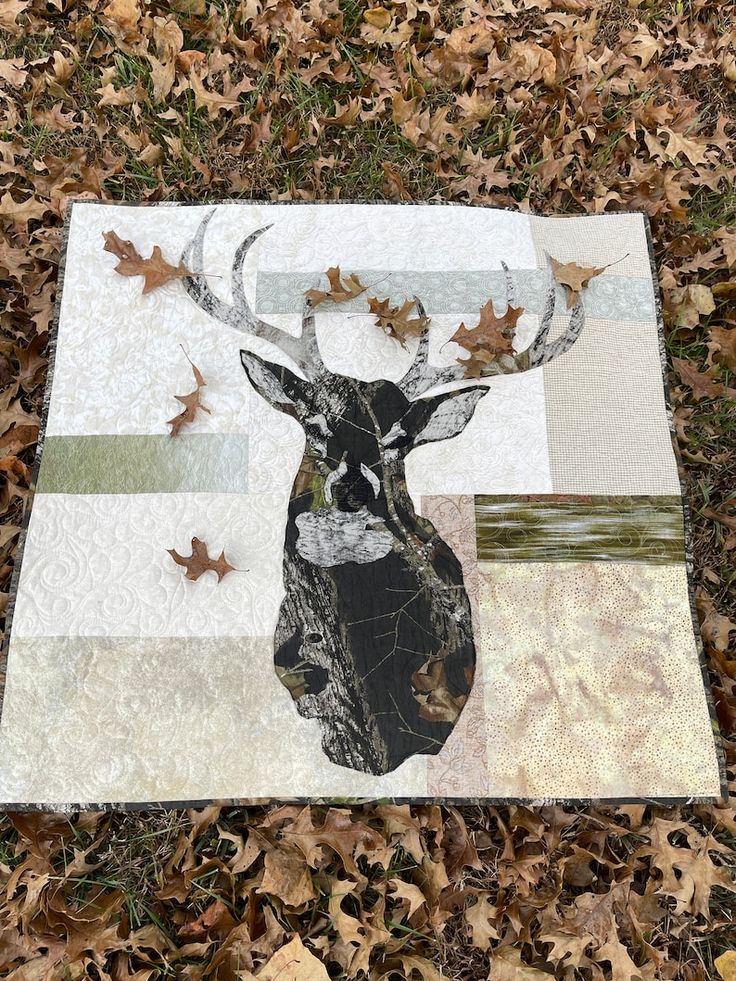 a quilted deer head on the ground surrounded by leaves