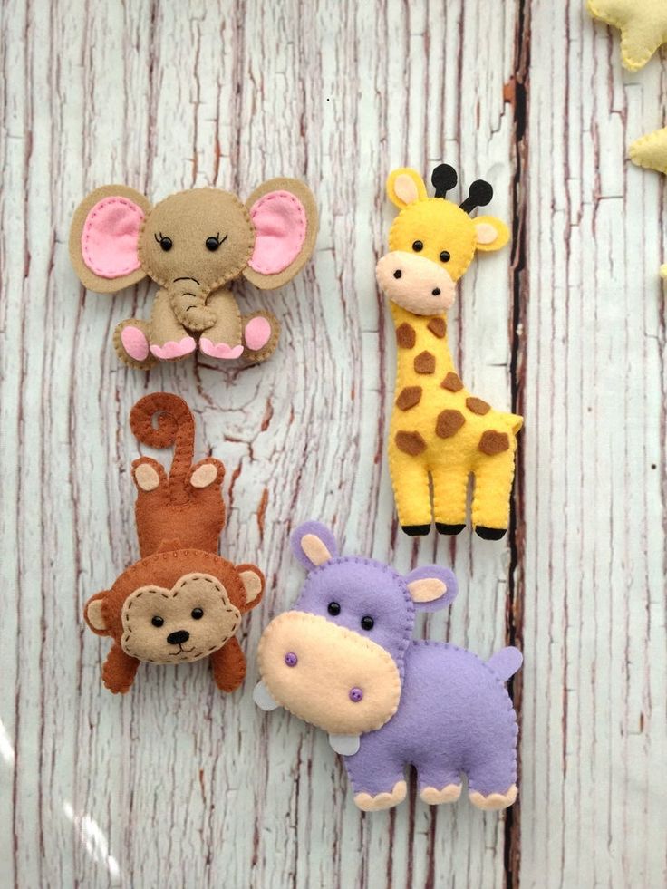 four felt animals are sitting on a wooden surface