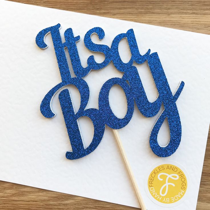 a cake topper that says it's a boy with blue glitter on it