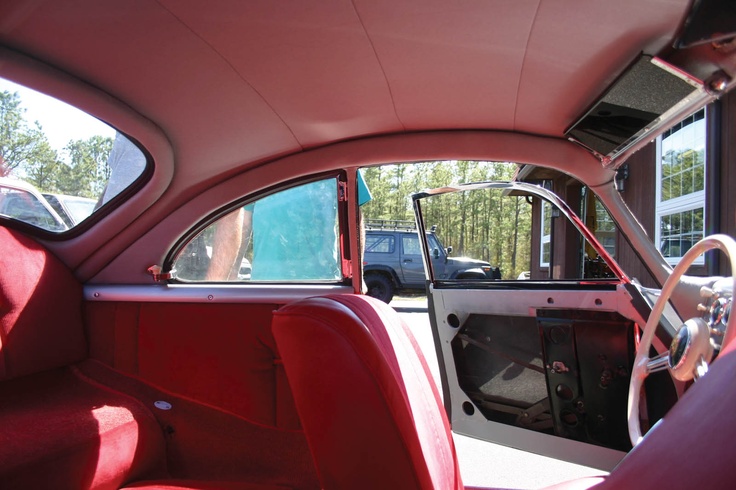 the interior of an old car with red leather seats and dash board, showing the driver's side door