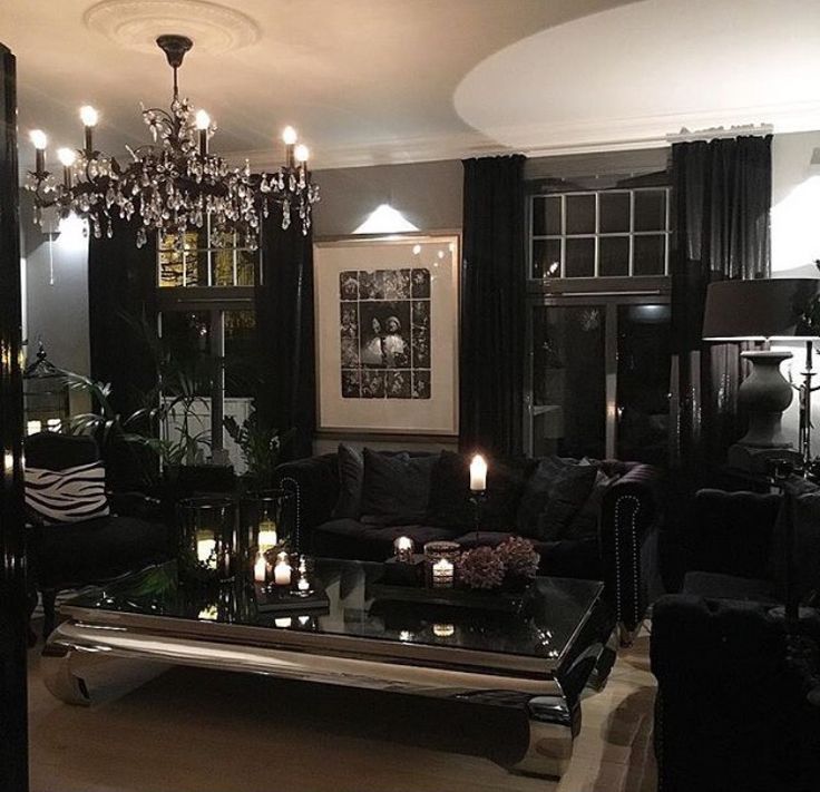 a living room filled with black furniture and lots of candles on top of the coffee table