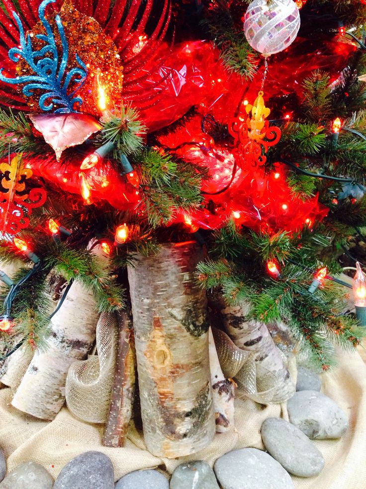 a christmas tree decorated with red, white and blue lights is surrounded by small rocks