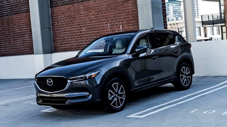 a black mazda cx - 5 parked in a parking lot next to a brick building