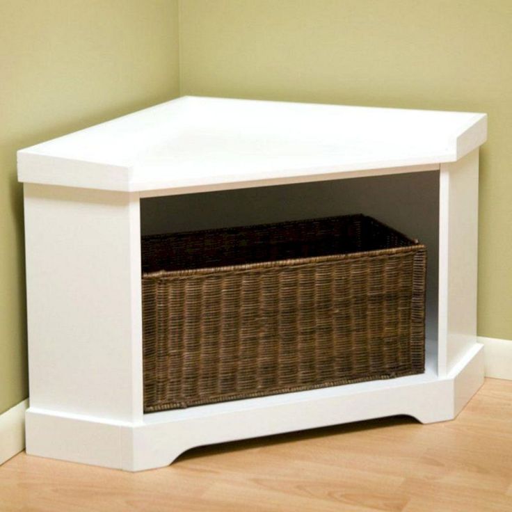 a white shelf with a wicker basket underneath it on the floor next to a wall