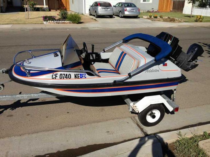 a white and blue speed boat parked on the side of the road next to a house