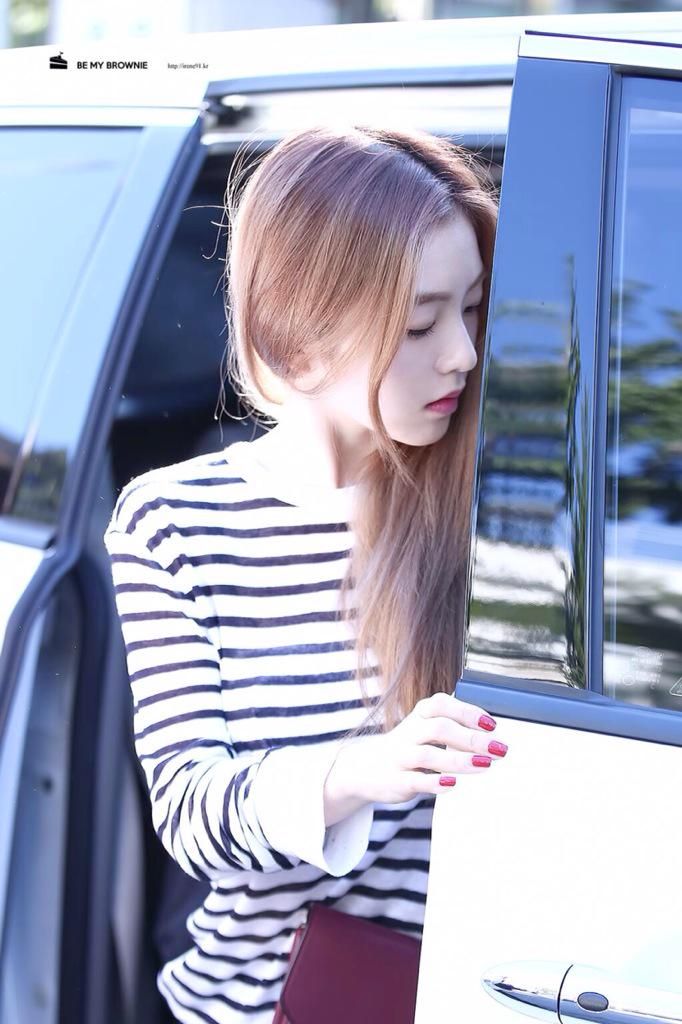 a woman with long hair standing next to a car