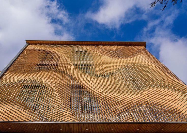 a building made out of woven material under a blue sky with wispy clouds