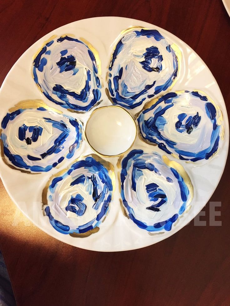 a white plate topped with blue and white flowers on top of a wooden table next to a bowl