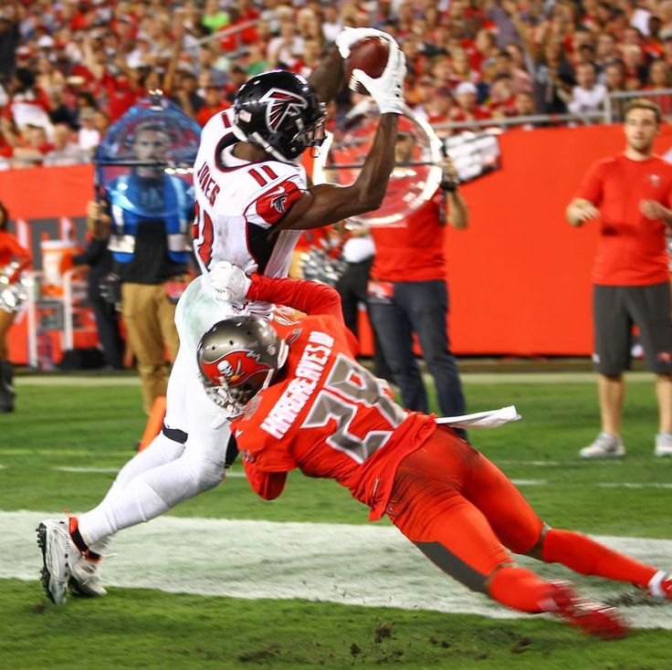 the football player is diving into the air to catch the ball while being tackled by another player