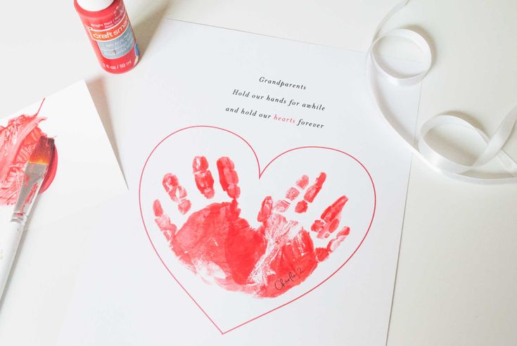 a heart shaped handprint on top of a piece of paper next to scissors and glue