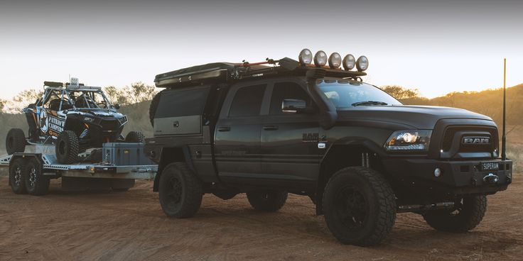 a black truck towing a atv behind it