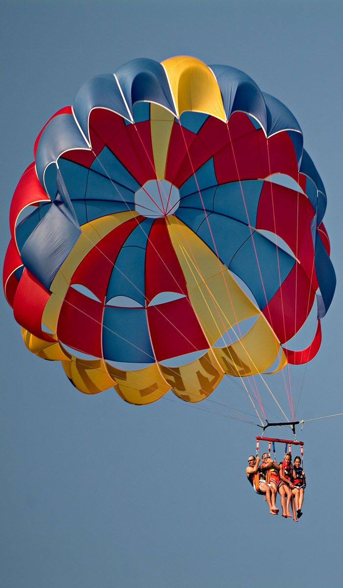 several people are parasailing in the air with parachutes attached to their backs