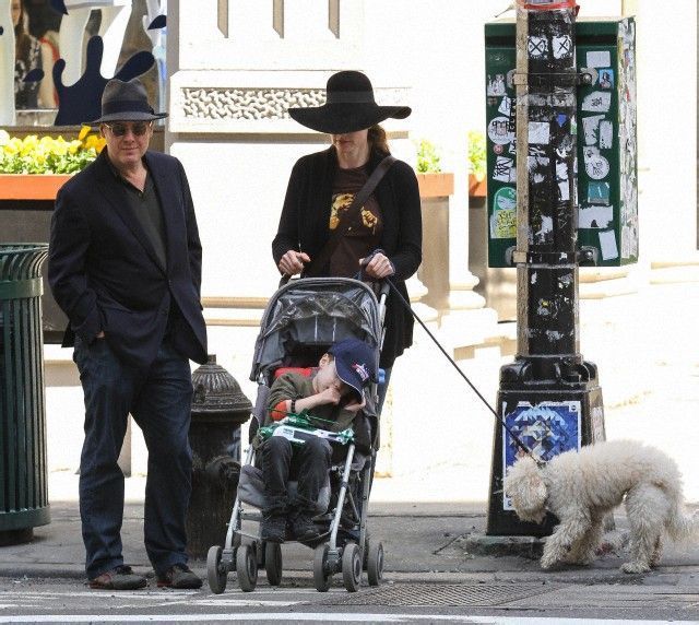 a man and woman are walking with a child in a stroller on the street