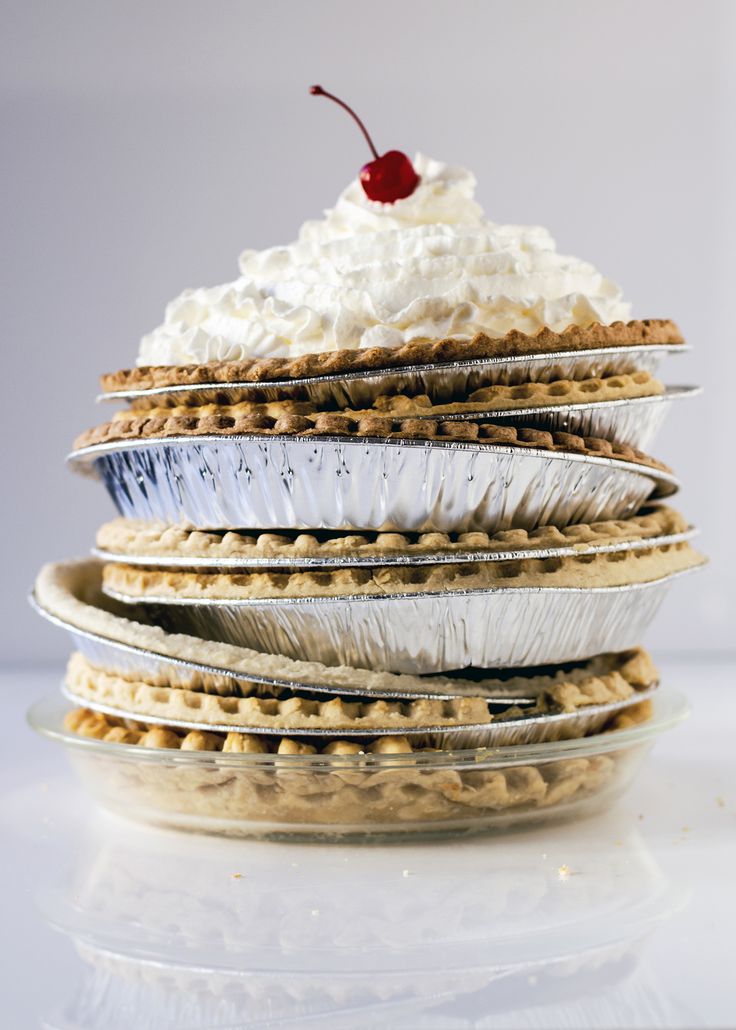 a stack of pies topped with whipped cream and a cherry sitting on top of each other