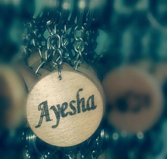 the word ayesia written on a round wooden sign hanging from chains in front of a computer keyboard