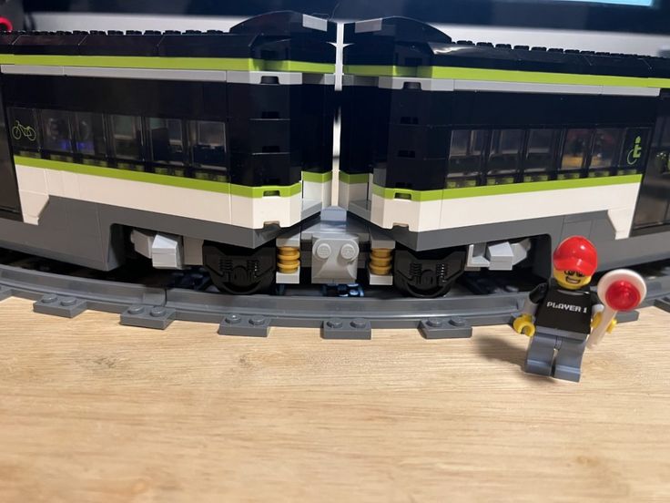 two legos are standing next to each other in front of a train