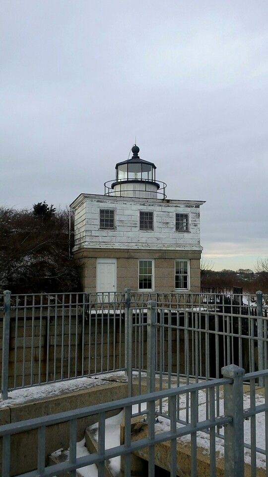 a light house sitting on top of a snow covered hill next to a fenced in area