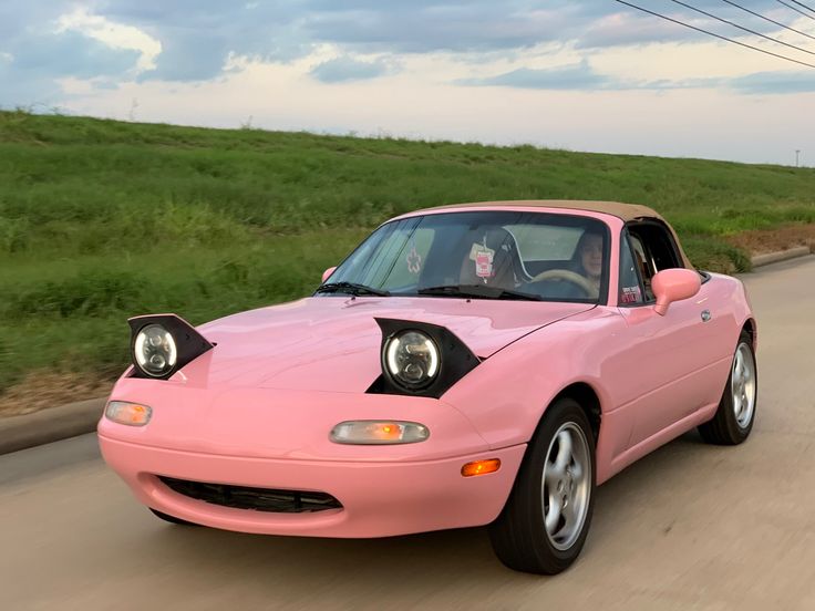 a pink sports car driving down the road