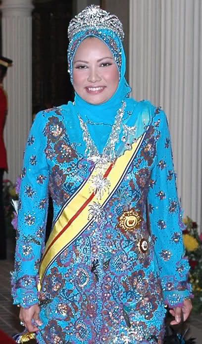 a woman wearing a blue and gold dress with a crown on her head, standing in front of a building